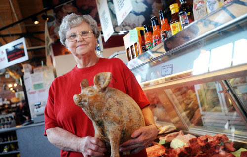 دوريس ويلي، مديرة متجر جوني للحوم الطازجة، تحمل دمية خنزير في متجرها أمس (جيف جنتير - أ ب)