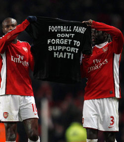 غالاس وسانيا لاعبا أرسنال الإنكليزي يرفعان لافتة يدعوان فيها جماهير كرة القدم إلى عدم نسيان دعم هايتي (ايدي كيوغ ــ رويترز)
