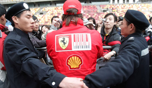 شرطيان يتولّيان حماية فرناندو ألونسو خلال توقيعه للمشجعين في شنغهاي (آن يونغ ـ جون ــ أ ب)