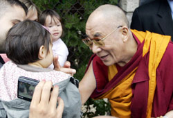 الدلاي لاما يداعب طفلة فرنسية بعد افتتاحه معبداً جنوب فرنسا (ريمي دو لا موفينيار - أ ب)