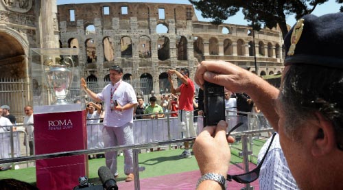 سائح يلتقط صورة تذكارية أمام كأس دوري أبطال أوروبا، وبدا خلفه ملعب الكولوسيوم الأثري، في روما (ملادين أونتونوف ــ أ ف ب)