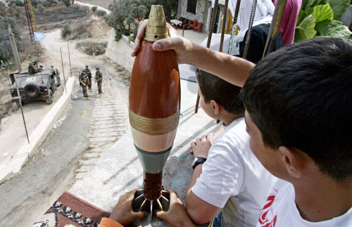 طفل جنوبي يعبث بقنبلة ويبدو حاجز للكتيبة الإسبانية  (أ ب)