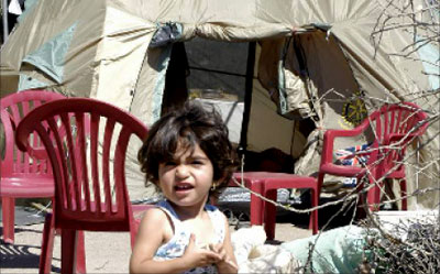 طفلة تلهو أمام خيمة نصبت مكان منزل ذويها