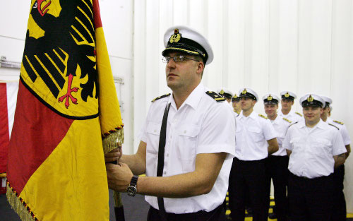 عنصر من البحرية الألمانية يرفع علم بلاده خلال حفل التسليم (أ ب)