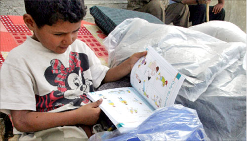 طفل من يارين يتصفّح كتاباً مقدّماً من إحدى المنظّمات الإنسانيّة (أ ف ب)
