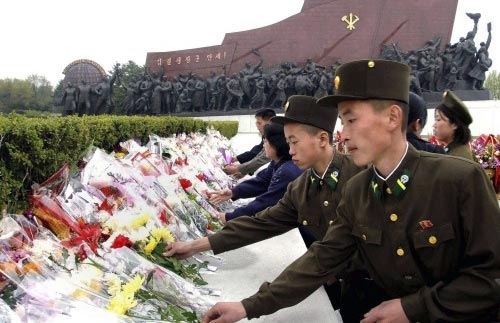جنود كوريون شماليون وطلاب يضعون الزهور على تمثال كيم ايل سونغ في بيونغ يانغ أول من أمس (رويترز)
