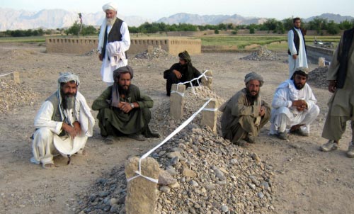 أفغان يجلسون بالقرب من أضرحة أقاربهم الذي قضوا في الغارة الأميركية على قرية غارني (أ ف ب)